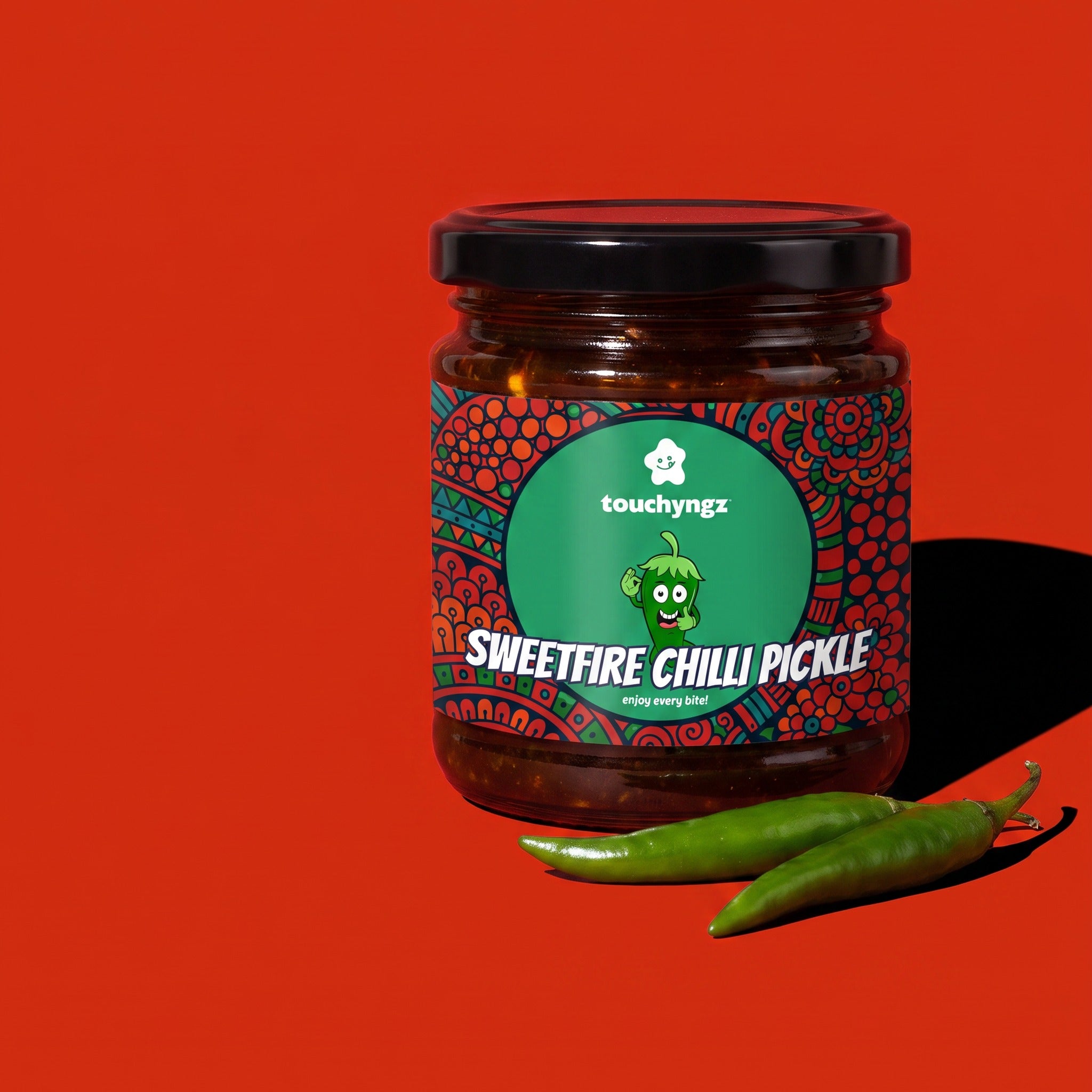 SweetFire Chilli Pickle 200g jar by Touchyngz on red background with green chillies