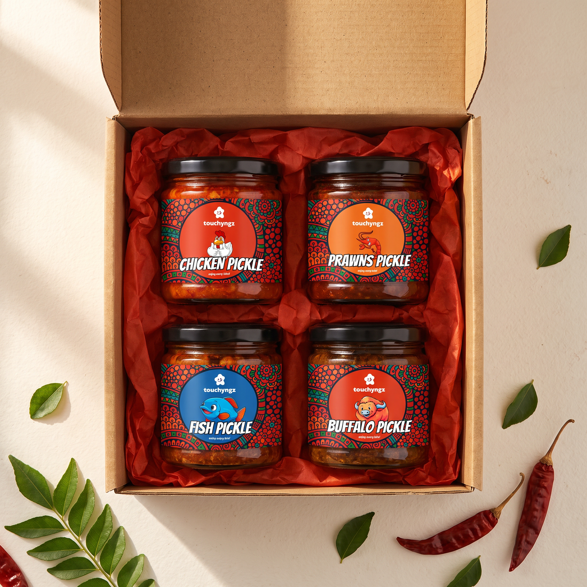 Taste of Kerala Non-Veg Pickle Gift Box by Touchyngz — Chicken, Prawns, Tuna and Buffalo pickle jars in an open kraft gift box with red tissue paper